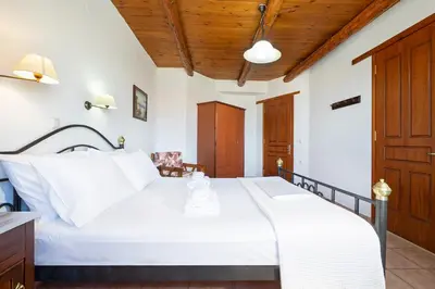 a bedroom with a large white bed and wooden ceilings at 4-bedroom Topolia House in Topólia