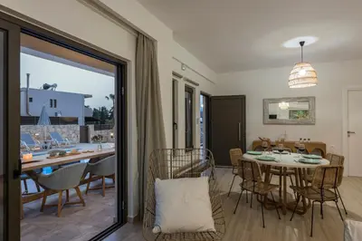 a dining room and living room with a table and chairs at Villa Kambos Platanias in Plataniás