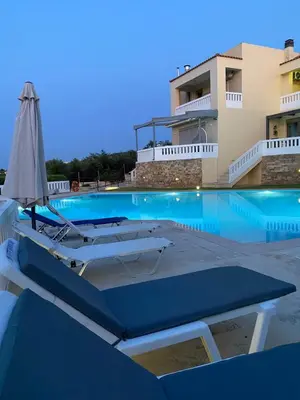 a swimming pool with a boat and an umbrella at Villa Pandora - Petit Bonheur in Maleme