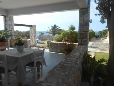 a patio with a table and chairs on a stone wall at Serenity Hideaway in Palaiochóra