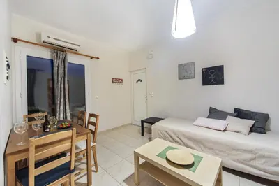 a living room with a bed and a table at Omega Comfy Apartments in Almirida