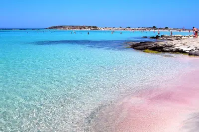 a beach with people swimming in the water at Omega Comfy Apartments in Almirida