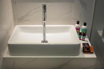 a white sink with a faucet in a bathroom at Aequor Luxury Rooms & Apartments in Kato Daratso