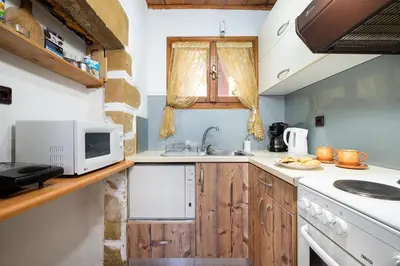 a kitchen with wooden cabinets and a microwave at Topolia 1 Bedroom Villa in Topólia