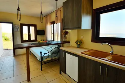 a kitchen with a sink and a table in it at Kalithea Studio Aptera in Megála Khoráfia