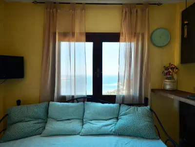 a living room with a couch in front of a window at Kalithea Studio Aptera in Megála Khoráfia