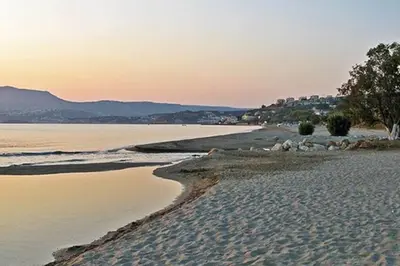 a sandy beach with rocks and the ocean at sunset at Kalithea Studio Aptera in Megála Khoráfia