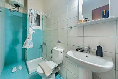 a blue and white bathroom with a sink and a toilet at Omega Comfy Apartments Almyrida in Almirida