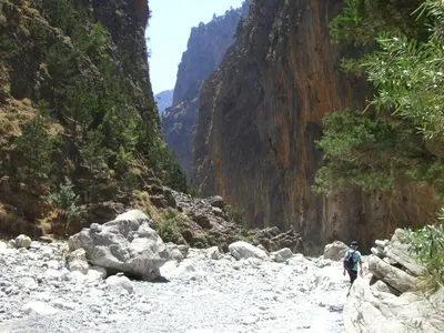 a person walking down a rocky river in a canyon at Omega Comfy Apartments Almyrida in Almirida