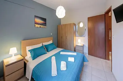 a bedroom with a blue bed with two towels on it at Omega Comfy Apartments Almyrida in Almirida