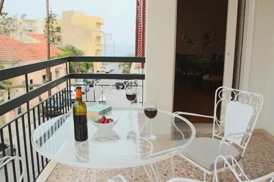 a glass table with two glasses of wine on a balcony at Spacious townhouse close to Chania center in Chania Town