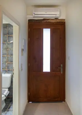 a bathroom with a wooden door and a sink at Feneri- cozy Apartment 20' from Elafonisi beach in Elafonisi