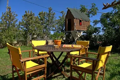 a table and chairs with a bird house in the background at Diamant's Place with Treehouse Garden in Kounoupidhianá