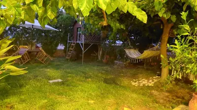 a yard with chairs and a table and an umbrella at Diamant's Place with Treehouse Garden in Kounoupidhianá