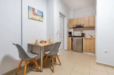 a kitchen with a table and chairs in a room at Sun Beach Apartments in Kato Daratso