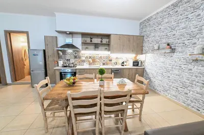 a kitchen and dining room with a wooden table and chairs at Stelios & Stavros Apartment in Kissamos