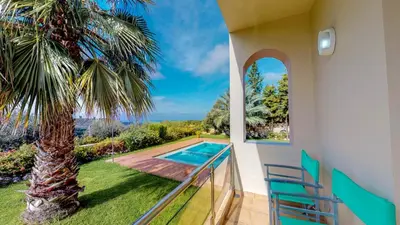 a house with a balcony with a palm tree and a swimming pool at Meliades Villas in Agia Marina Nea Kydonias