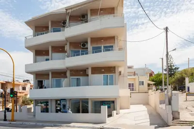 a tall white building on the corner of a street at Lily of Crete 1 - Sea & Beach front Apartment in Kalamaki Chanion