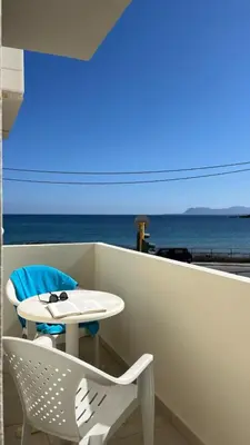 a table and a chair on a balcony with the ocean at Lily of Crete 1 - Sea & Beach front Apartment in Kalamaki Chanion