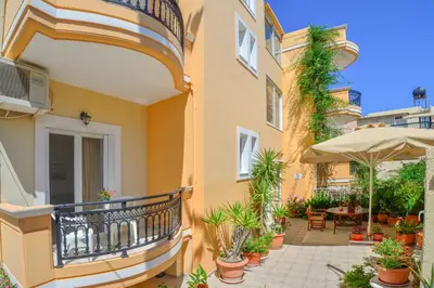a balcony of a building with plants and an umbrella at Villa Mimagia Apartments in Palaiochóra