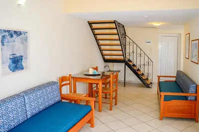 a living room with chairs and a table and a staircase at Villa Mimagia Apartments in Palaiochóra