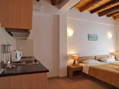 a bedroom with a bed and a kitchen with a stove at Villa Niki in Loutro