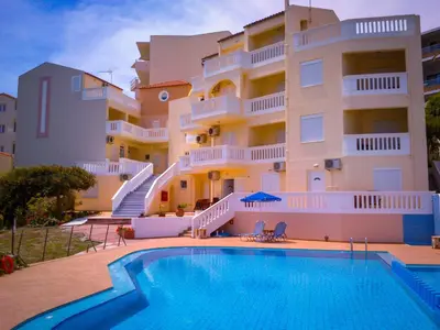 a building with a swimming pool in front of a building at Kalimera Hotel in Agia Marina Nea Kydonias