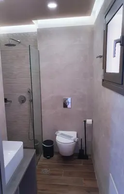 a bathroom with a toilet and a shower and a sink at Kalimera Hotel in Agia Marina Nea Kydonias