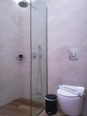 a bathroom with a shower with a toilet and a glass door at Kalimera Hotel in Agia Marina Nea Kydonias