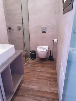 a bathroom with a toilet and a glass shower at Kalimera Hotel in Agia Marina Nea Kydonias