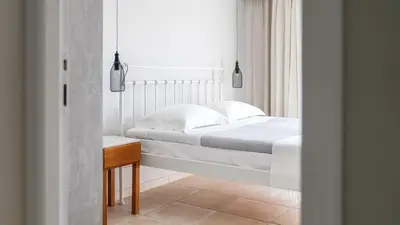 a white bedroom with a bed and a table at The Mini Beach Hotel in Stalos