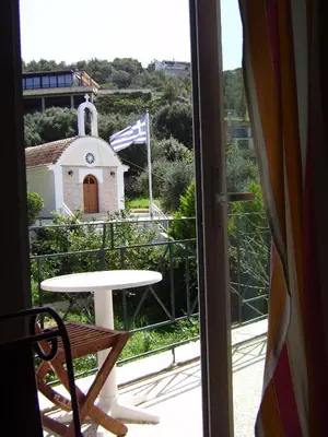 a table and chair on a balcony with a church at Akrotiri Hotel in Chania Town
