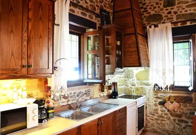 a kitchen with wooden cabinets and a sink at Kamara Stone House in Kissamos