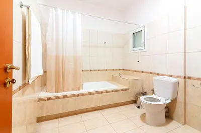 a bathroom with a toilet and a bath tub at Charming and Comfy House in Agia Marina Nea Kydonias