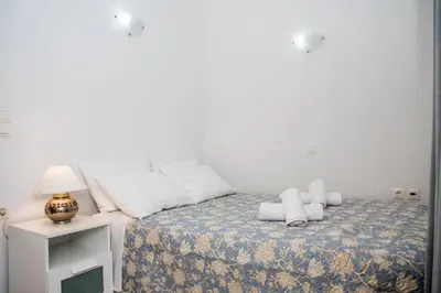 a white bedroom with a bed with pillows and a lamp at Nikis Apartment in Chania Town