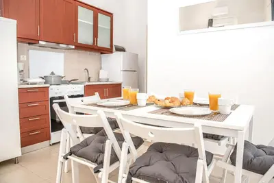a kitchen with a white table with chairs and orange juice at Nikis Apartment in Chania Town