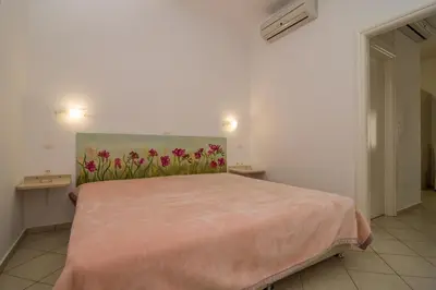 a bedroom with a pink bed with a painting on the wall at Manto Studios in Palaiochóra