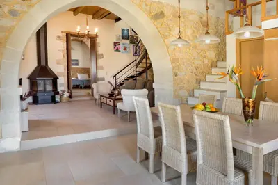 a dining room with a table and chairs and a stone wall at Olga's Filoxenia - Villa Aladanos-private pool and heated jacuzzi in Makhairoí