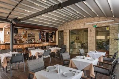 a restaurant with white tables and chairs and a bar at Elotis Suites in Agia Marina Nea Kydonias