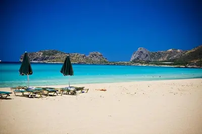 a beach with chairs and umbrellas and the ocean at Ilia's Apt in Chania in Chania Town
