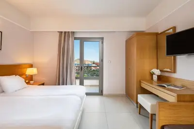 a hotel room with a bed and a desk with a television at Porto Platanias Village Resort in Plataniás
