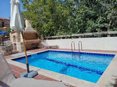 a swimming pool with an umbrella next to a fence at Douliana Villas in Douliana