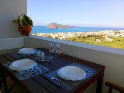 a table with plates and glasses and a view of the ocean at Thea Apartment in Agia Marina Nea Kydonias