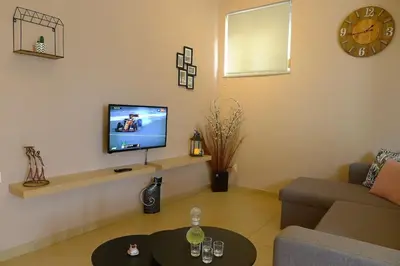 a living room with a couch and a tv on a wall at Maria & Manos Guest House, Agios Onoufrios beach in Agios Onoufrios