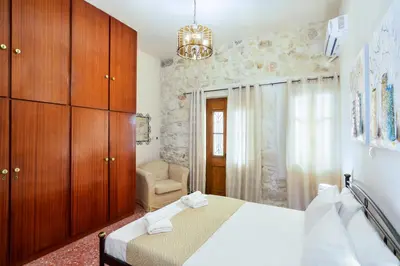 a bedroom with a bed with wooden cabinets and a chair at Michalis Stonehouse in Chania Town