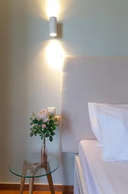 a vase with flowers on a table next to a bed at Girogiali beach hotel - Adults only in Stalos