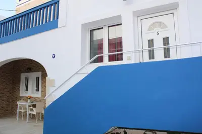 a staircase leading up to a house with a blue wall at Bay View Apartments in Plataniás