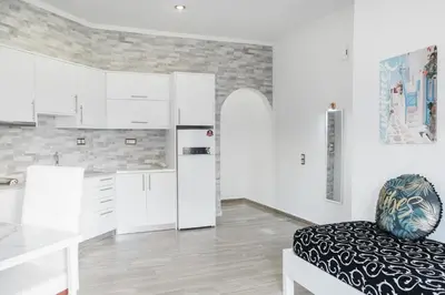 a kitchen with white cabinets and a chair at Bay View Apartments in Plataniás
