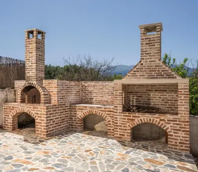 an outdoor brick oven with two chimneys on a patio at Villa Aphrodite in Alikianós