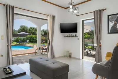 a living room with a view of a pool at Villa Aphrodite in Alikianós